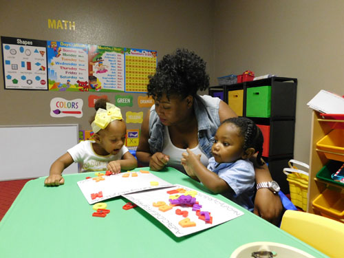 woman with two preschoolers at table in classroom