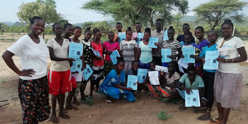 group of about 25 people standing outside holding booklets