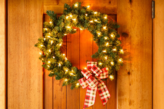 wreath hanging on door with LED white Christmas lights in wreath