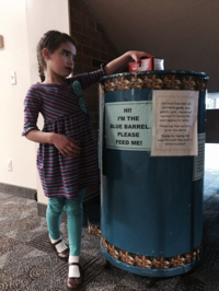 child putting food in the blue barrel